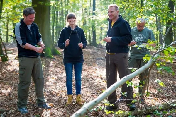 Vier Personen stehen im Wald und halten Seile in der Hand