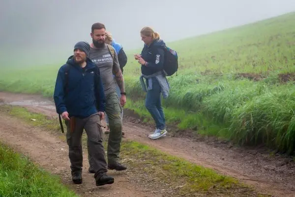 Wanderer mit Rucksäcken gehen einen schmalen Weg entlang in nebliger Umgebung