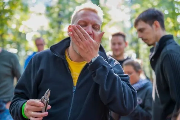 Zange in der Hand, Gesicht mit der Hand berührt, konzentrierter Ausdruck