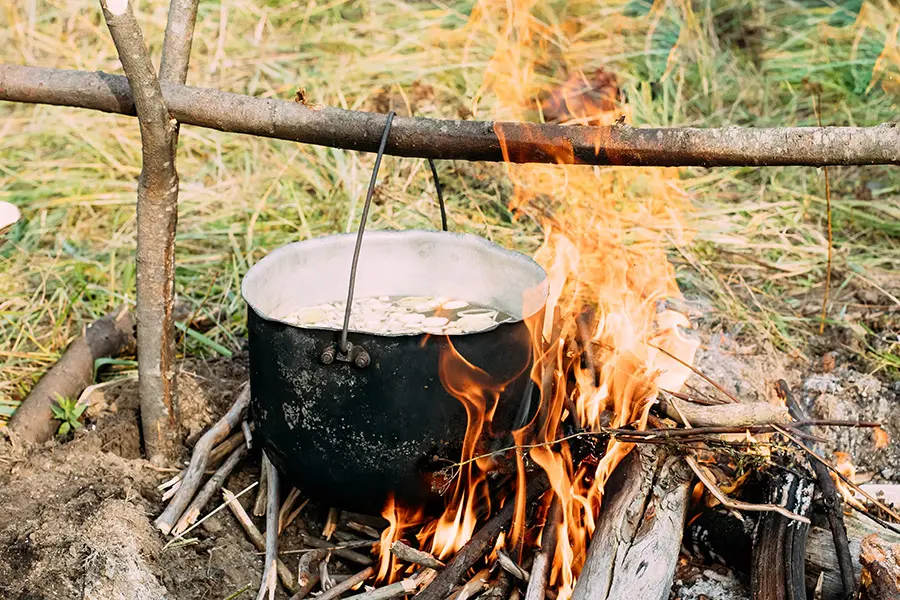 Wasser in einem Metallgefäß über dem Feuer abkochen