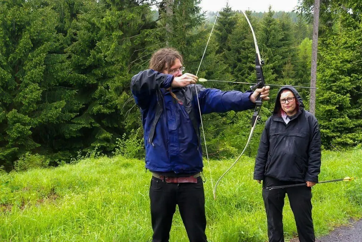Bogenschütze spannt Pfeil und Bogen in einer Waldlandschaft