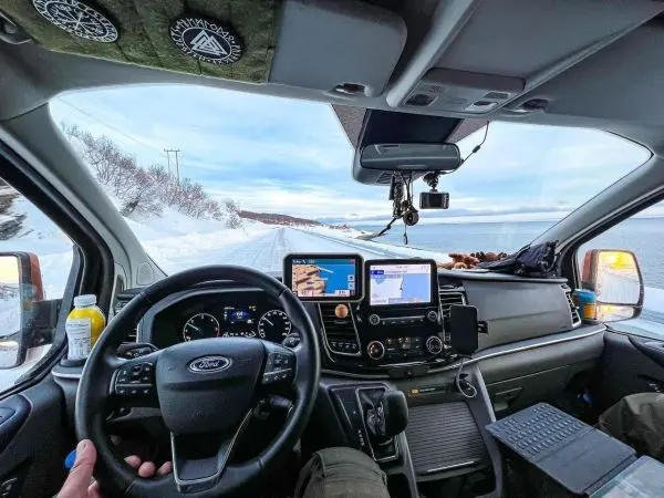 Cockpit eines Fahrzeugs mit Blick auf eine verschneite Straße und Wasser