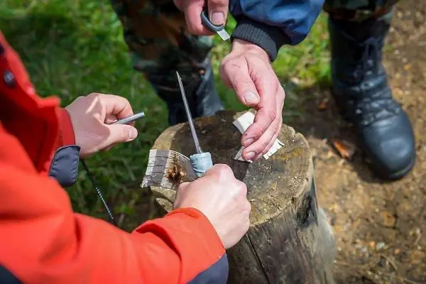 Feuerstahl erzeugt Funken auf Zunder auf einem Baumstumpf