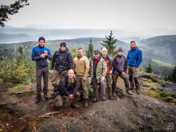 Gruppe steht auf einem Felsen mit Blick auf bewaldete Hügel und Nebel