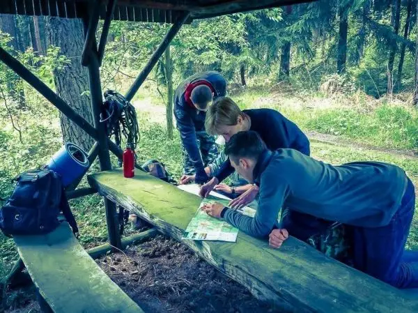 Gruppierung betrachtet Karte auf einer Holzbank unter einem Unterstand im Wald