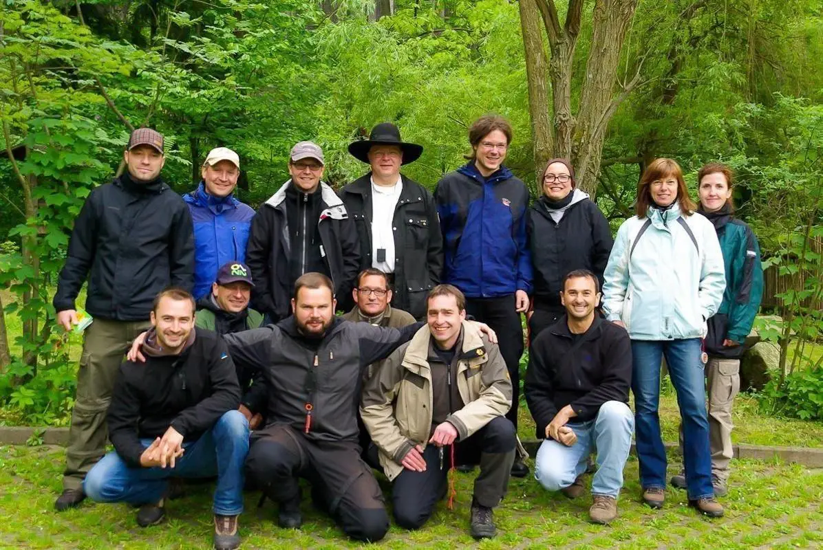 Gruppierung von Personen in einem grünen Waldgebiet, alle stehen oder sitzen zusammen
