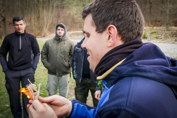Kleines Bodenfeuer entzündet Zunder in der Hand eines Teilnehmers