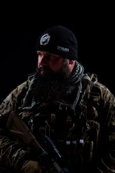 Mann in militärischer Ausrüstung hält ein Gewehr in der Hand