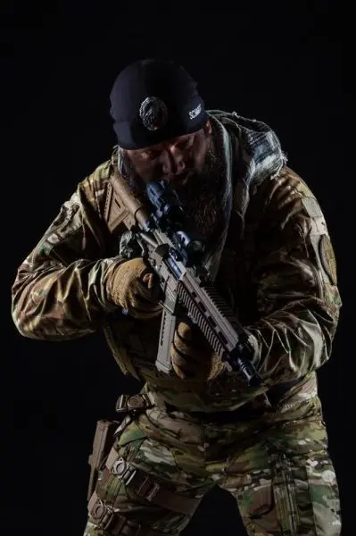 Mann in Tarnkleidung hält ein Gewehr in Schussposition