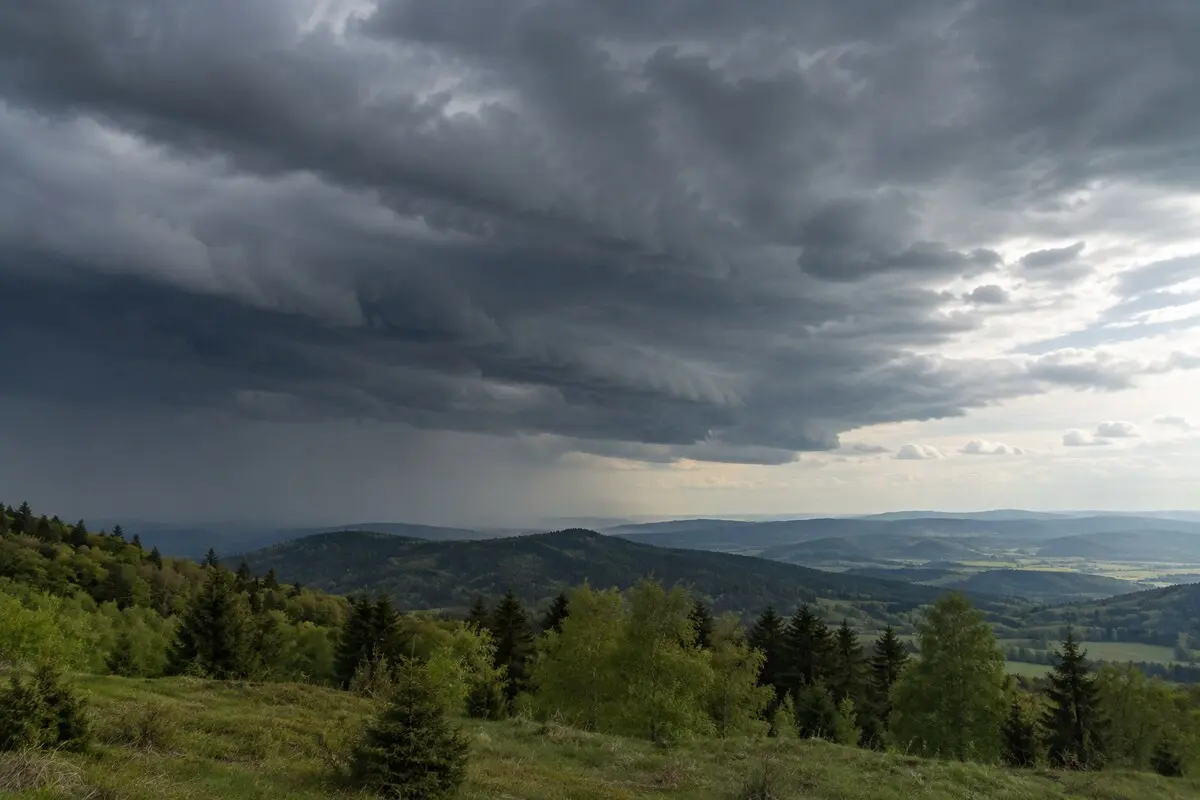 Dunkle, heranziehende Schauer- und Frontbewölkung über einem bewaldeten Mittelgebirge