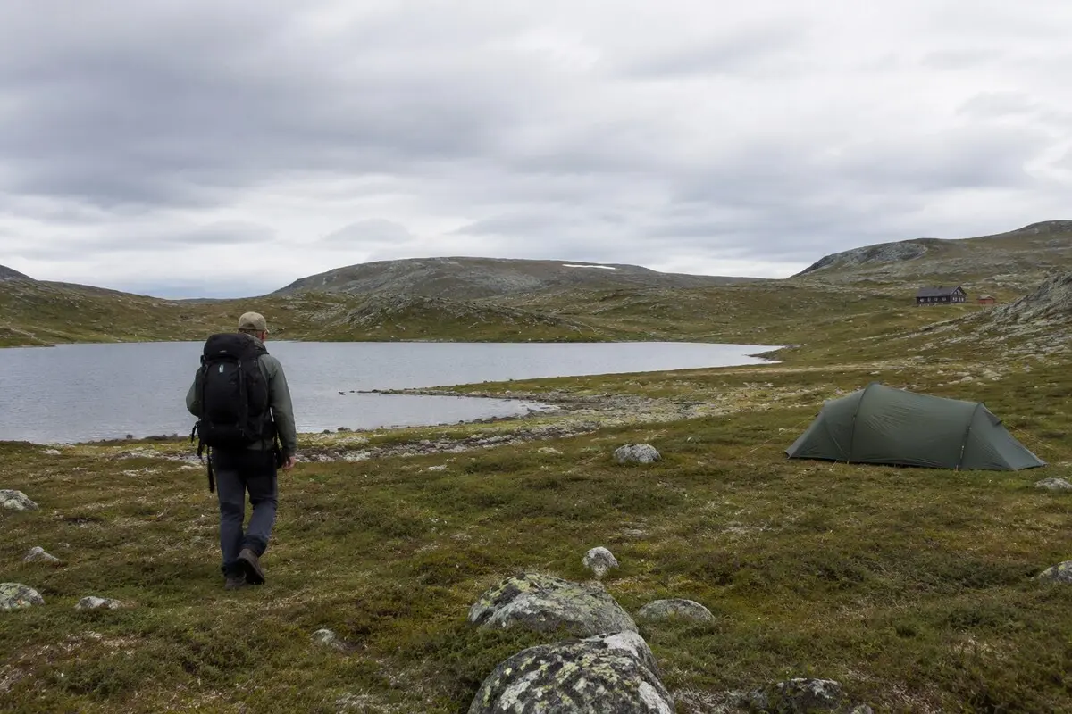 Wanderer und kleines Zelt in skandinavischer Landschaft