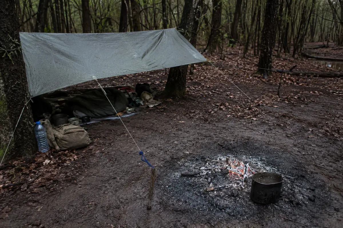 Survival-Lager mit Shelter, Feuerstelle und Wasserbehälter