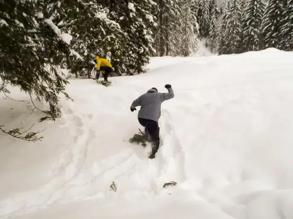 Mann bewegt sich durch tiefen Schnee in einem Waldgebiet