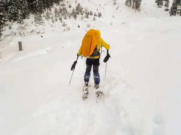Person mit Schneeschuhen und Rucksack geht durch tiefen Schnee