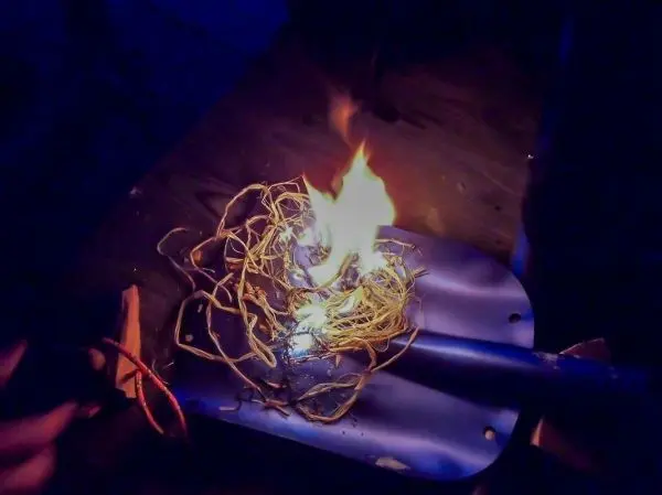 Zunder brennt auf einer Metallfläche mit Flammen und Glutnest